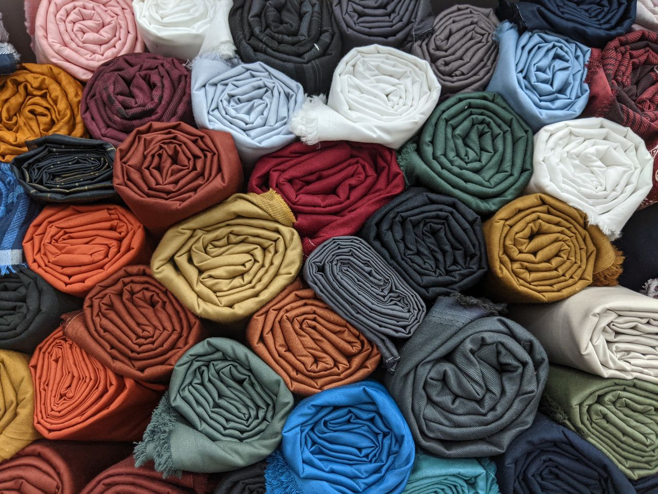 A vibrant and diverse collection of rolled fabrics in various colors, perfect for design inspiration.