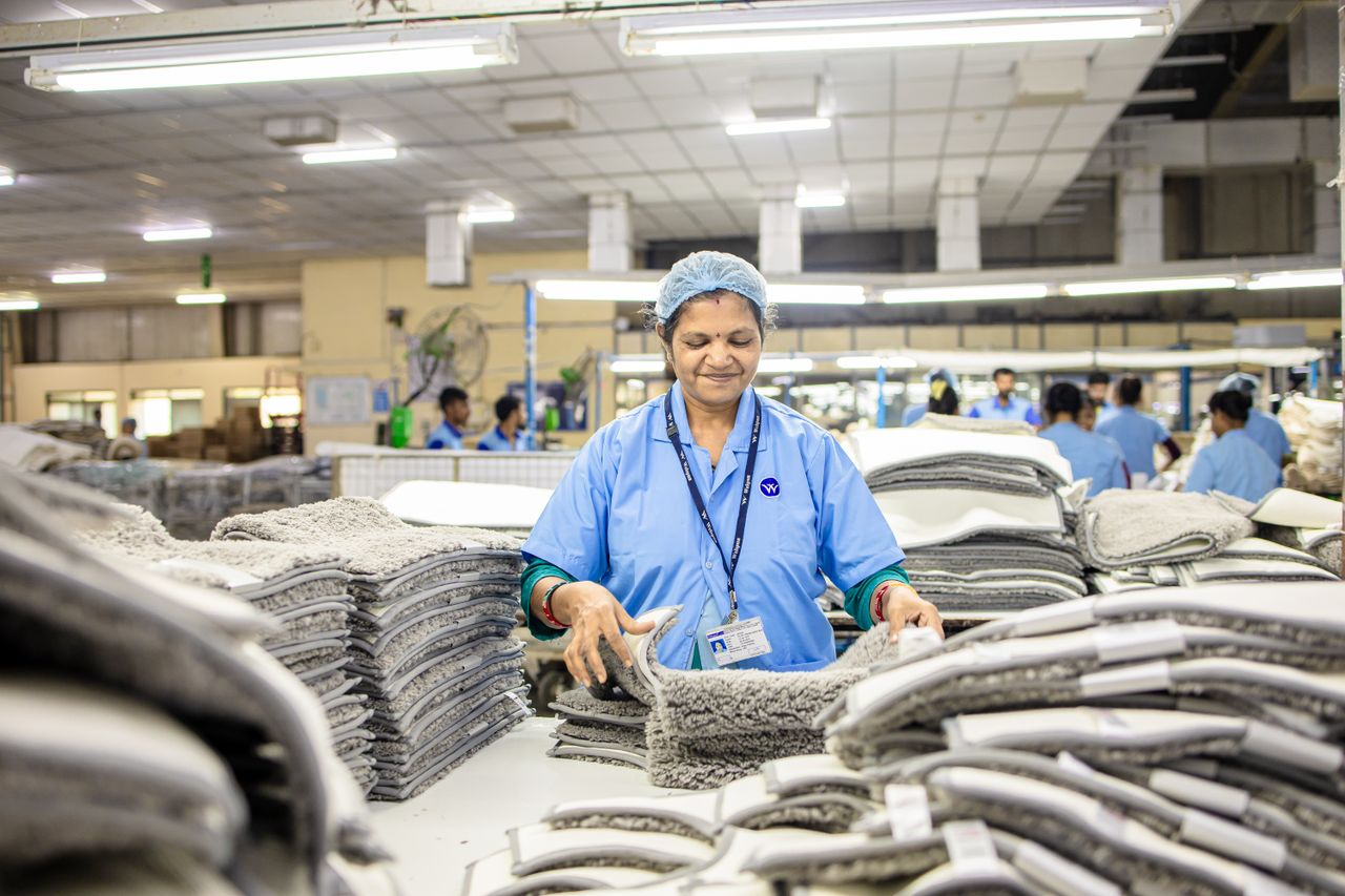 Woman in a textile factory sorting and organizing fabrics among colleagues in an industrial setting.