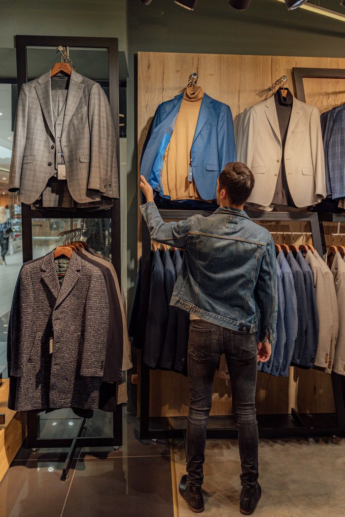 A man examines suits in a stylish fashion store display, highlighting modern shopping choices.